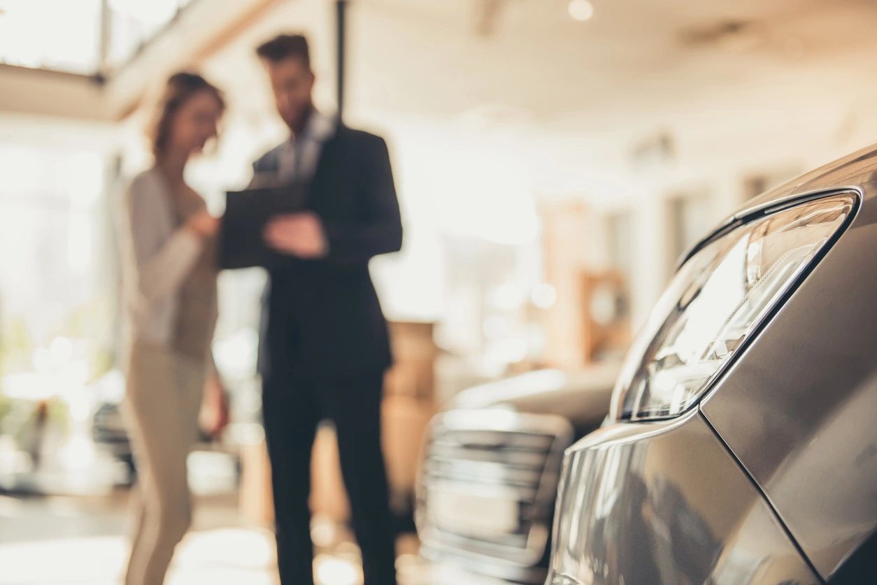 A man and woman in suits standing next to a car.