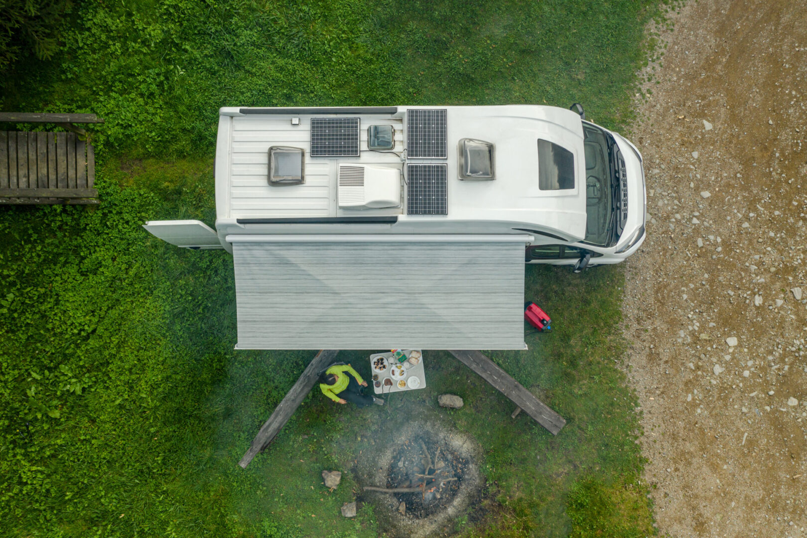 Recreational Vehicle Campground RV Park Pitch with Modern Camper Van Equipped with Solar Panels and Campfire Place Aerial View. Outdoor Weekend Getaway